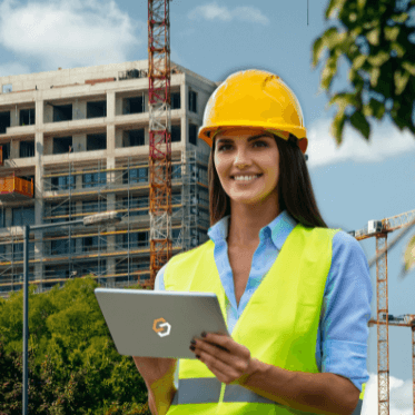 Female construction manager using a tablet on-site to oversee multi-site risk management at a large building project.