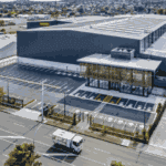 Aerial view of a modern industrial property with large warehouse buildings, parking spaces, and access roads, showcasing efficient site management and compliance.