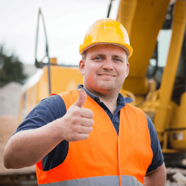 Construction worker in hard hat and hi-vis vest giving a thumbs up onsite for safety prequalification for contractors and compliant visitor site access.