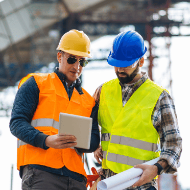 Construction compliance software helping site managers review project information on a tablet at an active construction site.