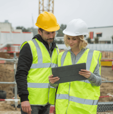 Construction workers completing digital contractor pre-qualification on a tablet to streamline contractor vetting and improve construction compliance.