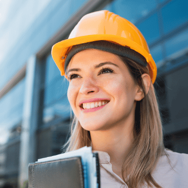 Woman wearing a hard hat and carrying safety documents (which could be replaced by a digital safety management system like SiteConnect) as part of workplace health and safety training.