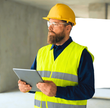 Construction manager wearing a hard hat and hi-vis vest using a tablet to streamline the contractor pre-qualification process and manage site compliance.
